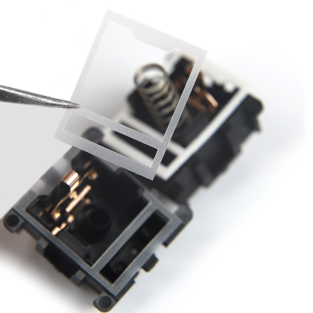 HTV 0.18mm switch film held in tweezers above an open Cherry MX style switch housing